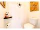 Neutral powder room with white toilet, wall art, and humorous, decorative toilet paper storage at 4545 S Ellesmere St, Gilbert, AZ 85297