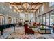 Expansive living room featuring stone walls, wood beams, chandeliers, piano, and elegant furniture at 678 E Cobble Stone Dr, Queen Creek, AZ 85140