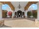 Elegant entrance featuring a stone archway, columns, mature flowers, brick driveway, and wrought iron chandelier at 8214 E Kael St, Mesa, AZ 85207