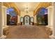 Impressive entrance featuring stone arches, columns, decorative iron gate, brick pavers, and custom lighting at 8214 E Kael St, Mesa, AZ 85207