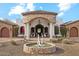 Grand entrance to home with stone archway, columns, fountain, desert landscaping, and wrought iron chandelier at 8214 E Kael St, Mesa, AZ 85207