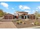 Beautiful home exterior with arched entryway, stone accents, fountain, long driveway, and desert landscaping at 8214 E Kael St, Mesa, AZ 85207