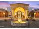 Striking residence boasting stone accents, arched entryway, beautiful landscaping, and inviting circular fountain at 8214 E Kael St, Mesa, AZ 85207