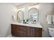 Luxurious bathroom with double sinks, marble countertops, modern fixtures, and an arch-framed mirror at 8432 E Keim Dr, Scottsdale, AZ 85250