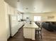 Open-concept kitchen boasts an island with seating, white cabinetry, and views into the adjacent living space at 8477 W Tinajas Dr, Arizona City, AZ 85123