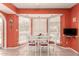 Bright dining room with a bay window, white table, white chairs with red cushions and an eye-catching orange paint at 8544 E San Lorenzo Dr, Scottsdale, AZ 85258