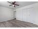 Bedroom with gray wood-look floors, white walls, a ceiling fan, and a double-door closet at 10846 W Sun City Blvd, Sun City, AZ 85351