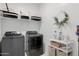 Functional laundry room with modern washer and dryer, storage shelves, and decorative wreath at 14254 W Cottontail Ln, Surprise, AZ 85387