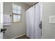 A well-lit bathroom with a shower featuring a patterned curtain and a window with blinds at 16993 W Shiloh Ave, Goodyear, AZ 85338