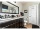 Bathroom featuring a double sink vanity with dark wood cabinets, granite countertop, and a large framed mirror at 16993 W Shiloh Ave, Goodyear, AZ 85338