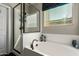 Bright bathroom showcasing a glass-enclosed shower, soaking tub, and a window with stylish patterned curtains at 16993 W Shiloh Ave, Goodyear, AZ 85338