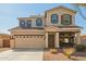 Two-story home featuring a charming front porch swing, a two car garage, and neutral toned exterior at 16993 W Shiloh Ave, Goodyear, AZ 85338