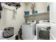 A compact laundry room with modern appliances, storage shelves and a decorative vase at 16993 W Shiloh Ave, Goodyear, AZ 85338