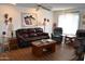 Cozy living room featuring a leather sofa, ceiling fan, and warm lighting at 17626 N Buntline Dr, Sun City West, AZ 85375