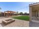 Inviting backyard with a fire pit, green lawn, stylish pergola, and desert surroundings at 1781 S 223Rd Dr, Buckeye, AZ 85326