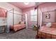 Charming bedroom featuring twin beds with canopies, soft carpet, and a playful pink color scheme at 1781 S 223Rd Dr, Buckeye, AZ 85326