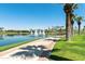 Scenic view of a community walking path alongside a lake with fountains and palm trees under a clear sky at 18501 W Galveston St, Goodyear, AZ 85338