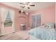 Pink bedroom featuring light wood flooring, a patterned bedspread, shelves, and bright natural light at 19259 N Ventana Ln, Maricopa, AZ 85138