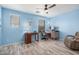 Bright bedroom with blue walls, wood-look floors, two expansive windows, and an area for work or study at 19259 N Ventana Ln, Maricopa, AZ 85138