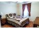 Relaxing bedroom showcasing wood-look flooring, a patterned quilt, and a large window at 1926 E El Moro Ave, Mesa, AZ 85204