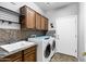 Functional laundry room featuring a utility sink, overhead cabinets, and modern appliances for convenience at 20207 N Riverbank Rd, Maricopa, AZ 85138