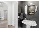 Elegant powder room with a pedestal sink, round mirror, and dark accent wall at 21432 N 77Th Pl, Scottsdale, AZ 85255