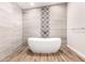 Clean bathroom showcasing freestanding tub, wood-look floors, natural stone accent wall for a spa-like retreat at 217 W Montecito Ave, Phoenix, AZ 85013