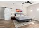 Bright bedroom features wood-look floors, minimalist decor, and a sliding barn door leading to en suite at 217 W Montecito Ave, Phoenix, AZ 85013