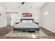 Spacious bedroom featuring wood-look floors, minimalist decor, and a sliding barn door leading to en suite at 217 W Montecito Ave, Phoenix, AZ 85013