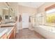 Well-lit bathroom with double sinks, a soaking tub, and a separate shower with golden-colored trim at 23034 N Pedregosa Dr, Sun City West, AZ 85375