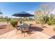 Charming patio featuring an outdoor dining set with a blue umbrella and views of the golf course at 23034 N Pedregosa Dr, Sun City West, AZ 85375