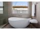 This luxurious bathroom has a freestanding tub, designer stool, and a window with a view at 2642 N Fiesta St, Scottsdale, AZ 85257