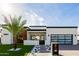 Beautiful modern home featuring a pristine lawn, palm trees, and a stylish glass garage door under a bright, sunny sky at 2642 N Fiesta St, Scottsdale, AZ 85257