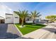 Modern home showcasing a manicured green lawn, gravel driveway, and palm trees under a clear blue sky at 2642 N Fiesta St, Scottsdale, AZ 85257