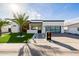 Beautiful modern home featuring a pristine lawn, palm trees, and a stylish glass garage door under a bright, sunny sky at 2642 N Fiesta St, Scottsdale, AZ 85257