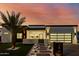 Modern home showcasing a well-lit pathway, glass garage door, and freshly landscaped front yard at dusk at 2642 N Fiesta St, Scottsdale, AZ 85257