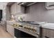 Close-up of stainless steel stove with gold knobs and gray tiled backsplash in modern kitchen at 2643 N Fiesta St, Scottsdale, AZ 85257