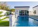 Poolside view with a waterfall feature, lush landscaping, and a modern cabana in the background at 2643 N Fiesta St, Scottsdale, AZ 85257