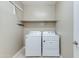 Bright laundry room with white washer and dryer, shelving, and tiled flooring at 287 N Jesse St, Chandler, AZ 85225