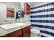 Well-lit bathroom features a granite countertop vanity, toilet, and shower with a blue striped curtain at 354 W Bealey Ave, Coolidge, AZ 85128