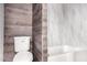 Bathroom featuring wood-look accent wall, a white toilet, and a tub with a light gray tile surround at 354 W Bealey Ave, Coolidge, AZ 85128