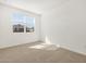 Bright bedroom with neutral carpet, white walls, and a large window at 37056 W Prado St, Maricopa, AZ 85138