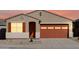 A charming single-Gathering home featuring a desert front yard, an orange garage door and complementary shutters at 37056 W Prado St, Maricopa, AZ 85138