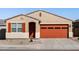 Charming single-story home showcasing a desert landscape, and an eye-catching orange garage door with matching shutters at 37056 W Prado St, Maricopa, AZ 85138