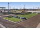 Outdoor game area with benches, cornhole, and turf in a well-maintained community space at 37056 W Prado St, Maricopa, AZ 85138