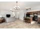 Open living room with tile flooring, chandelier, ceiling fan, grey sofa, and a view of the kitchen and dining area at 39242 N Luke Cir, San Tan Valley, AZ 85140