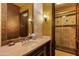 Elegant bathroom with a large mirror, stone countertops, and a glass-enclosed shower at 42237 N 107Th Pl, Scottsdale, AZ 85262