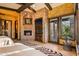 Spacious bedroom with a stone fireplace, built in TV, wooden ceiling beams and outside access at 42237 N 107Th Pl, Scottsdale, AZ 85262