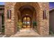 Close-up of home's arched stone entrance with wrought iron door and beautiful outdoor lighting at 42237 N 107Th Pl, Scottsdale, AZ 85262