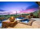 Inviting pool area with outdoor fireplace, spa, desert views and colorful sky at 42237 N 107Th Pl, Scottsdale, AZ 85262